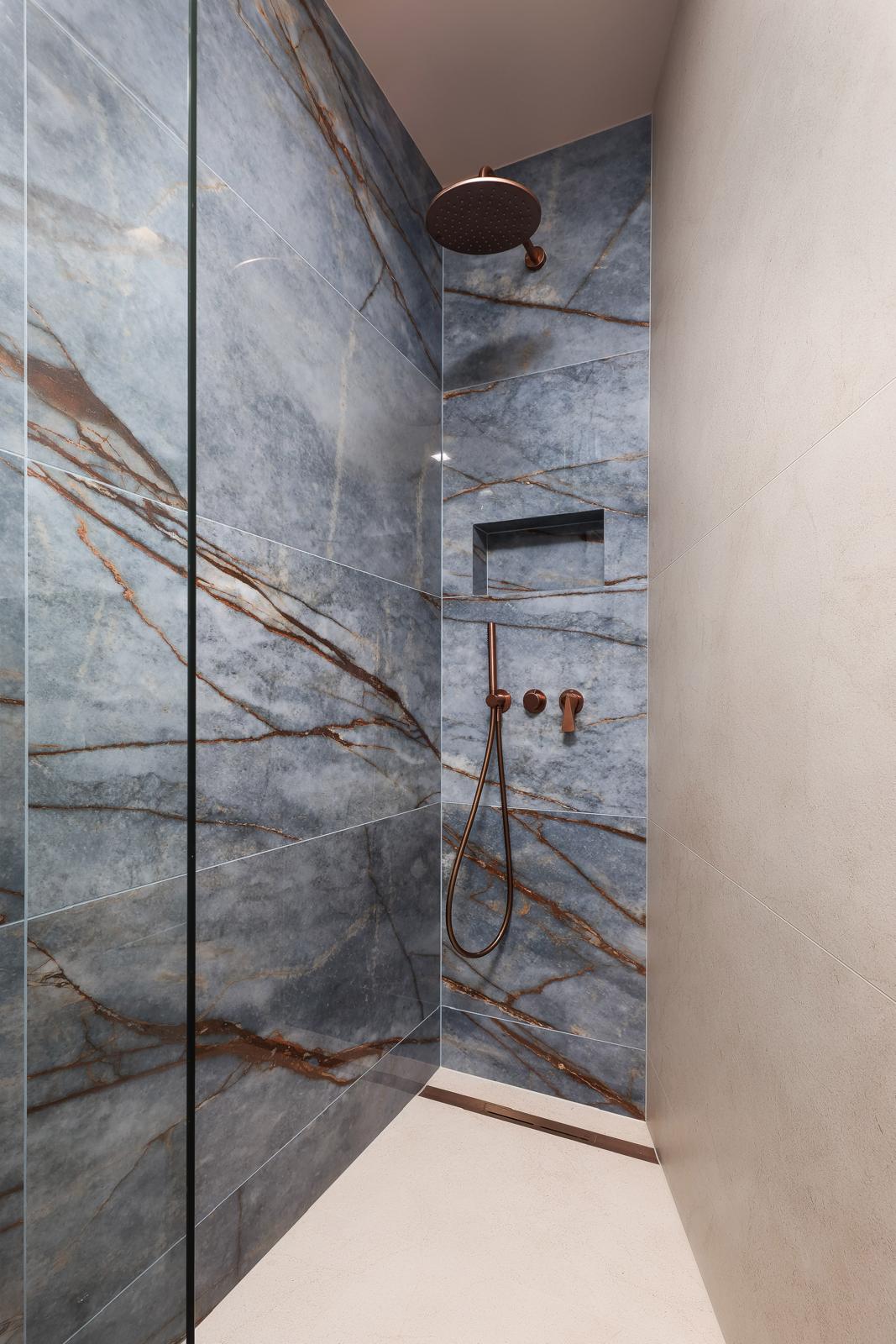 Walk-in rain shower with blue marble and copper fittings in the villa bathroom