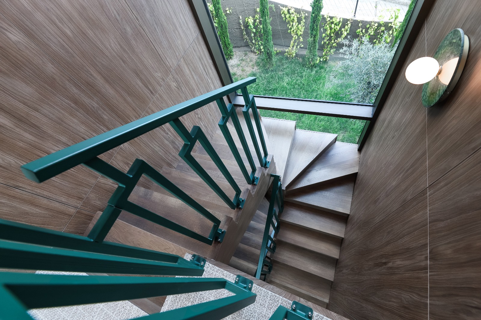 Sculptural oak staircase with emerald green railing inside the villa